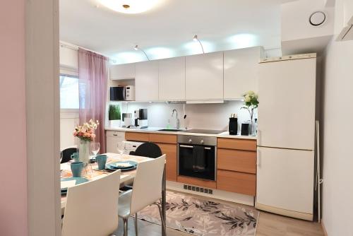 uma cozinha com armários brancos e uma mesa com cadeiras em Helsinki Seaside Home with Free Parking em Helsinque