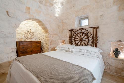 ein Schlafzimmer mit einem Bett und einer Holzkommode in der Unterkunft Trullo Saraceno in Ostuni