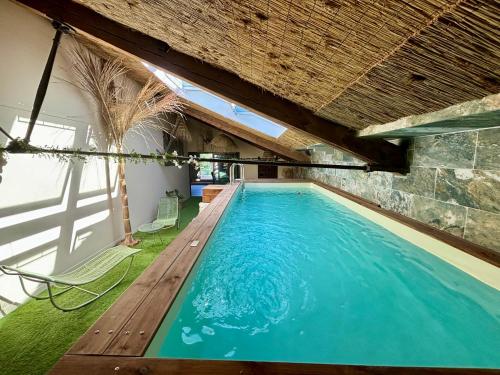 une piscine intérieure avec une terrasse en bois et une piscine dans l'établissement La cave de Grand Cabane, à Fourques