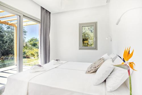 a white bedroom with a bed and a window at Kumquart estate- Kumquat in Aspiotádes