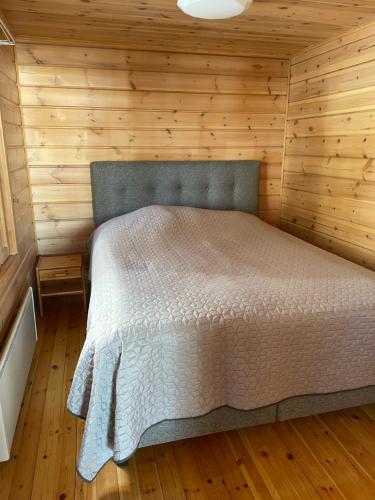 - une chambre avec un lit dans une pièce en bois dans l'établissement Huvila Pahkaranta Lestijärven rannalla, à Lestijärvi