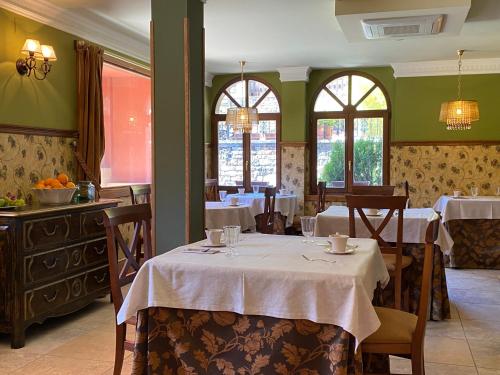 un comedor con mesas, sillas y ventanas en Hotel Finca Malvasia, en Cabezón de Liébana