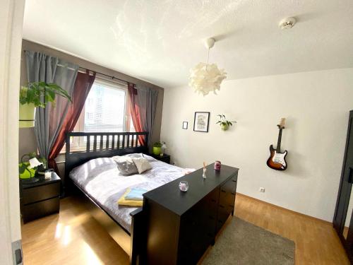 een slaapkamer met een bed, een bureau en een gitaar bij Komplette Wohnung nahe am See in Prenzlau