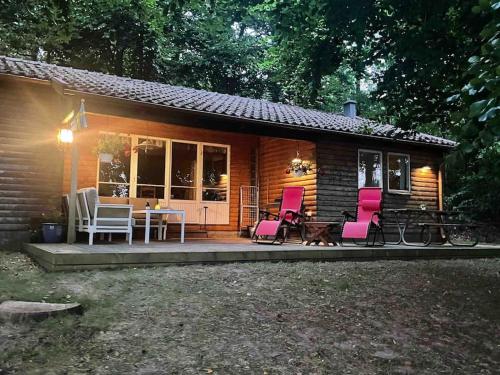 a small cabin with pink chairs and a table at Lönnekullen, enkel sommarstuga mitt i skogen på Österlen med dusch ute in Gärsnäs