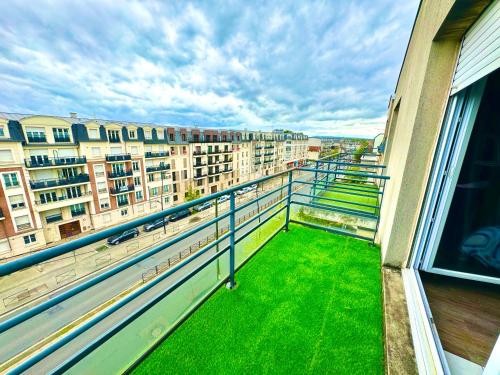 d'un balcon avec de l'herbe verte et des bâtiments en arrière-plan. dans l'établissement Appartement Cosy proche Paris La Défense, à Sartrouville