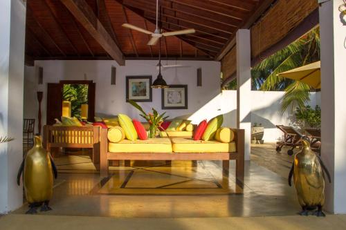 a living room with a yellow couch with colorful pillows at The Saffron House in Dickwella