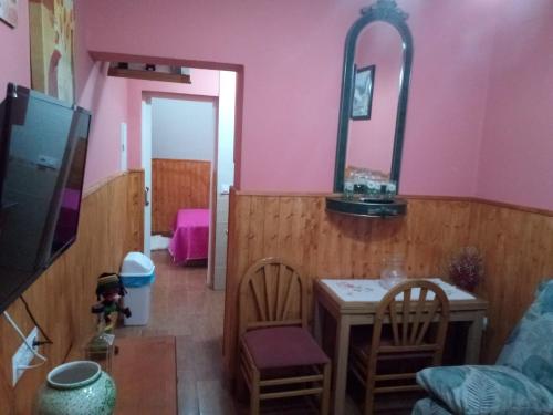 a living room with pink walls and a table and chairs at Apartamento araceli in Chipiona