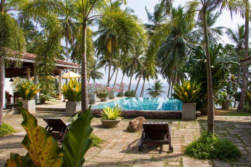 a resort with a swimming pool and palm trees at The Saffron House in Dickwella