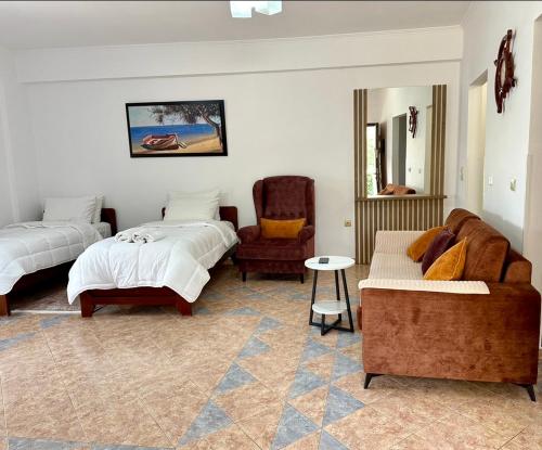 a bedroom with two beds and a couch and a chair at SHEMO Apartments in Sarandë