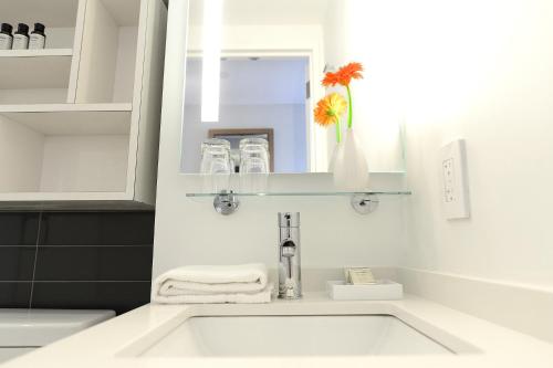 a white bathroom with a sink and a mirror at Edge Hotel Washington Heights in New York