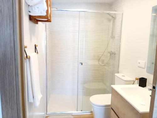 a white bathroom with a shower and a toilet at A PINTEGA DAS DUNAS in Ribeira