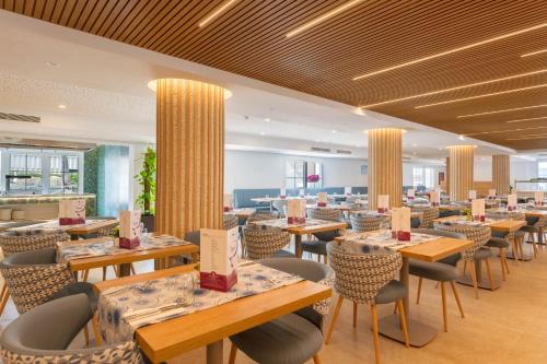 a restaurant with tables and chairs in a room at Hotel Capricho in Cala Ratjada