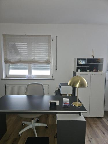 una oficina con escritorio con lámpara y ventana en FeWo "Quelle", en Bamberg