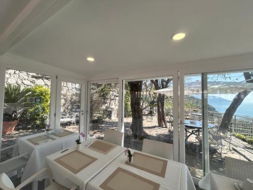 a white dining room with a view of the ocean at Villa Costanza sorrento B&b in Sant'Agnello