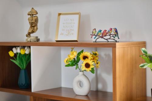a wooden shelf with a vase with flowers on it at Cherish Stays spacious & amazing 3 Bed House in Hayes & Heathrow in West Drayton