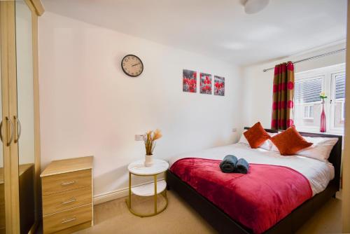 a bedroom with a bed and a clock on the wall at Cherish Stays spacious & amazing 3 Bed House in Hayes & Heathrow in West Drayton