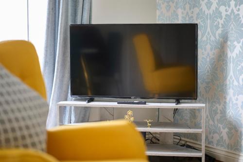 a flat screen tv sitting on a tv stand at Cherish Stays spacious & amazing 3 Bed House in Hayes & Heathrow in West Drayton