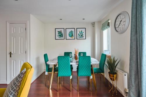 a dining room with a table and green chairs at Cherish Stays spacious & amazing 3 Bed House in Hayes & Heathrow in West Drayton