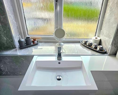 a bathroom sink with a mirror in front of a window at Family Home with Free Parking in Newton Mearns