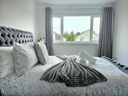 a bedroom with a bed with a large window at Family Home with Free Parking in Newton Mearns
