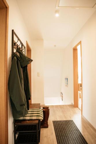 a room with a bench with a coat hanging on a wall at Ferienwohnung Hohner Seeblick in Hohn