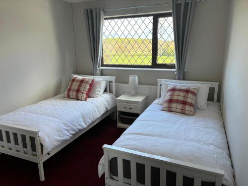 two beds in a room with a window at 2 Bedroom Bungalow in Rhosllanerchrugog