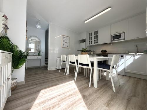 a kitchen and dining room with a white table and chairs at "LAS CAMELIAS SOMO" un lugar para desconectar!! Vistas al MAR!! in Somo