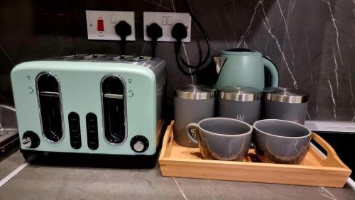 a toaster and two cups on a wooden tray at Entire, lovely apartment with a bath tub in Glasgow