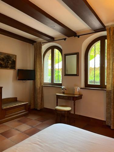 a bedroom with a bed and a table and windows at Le Château du Landsberg in Barr