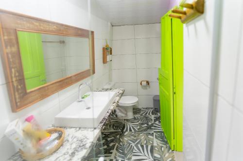 ein Badezimmer mit einem Waschbecken, einem Spiegel und einem WC in der Unterkunft Pousada Barari in Guarapari