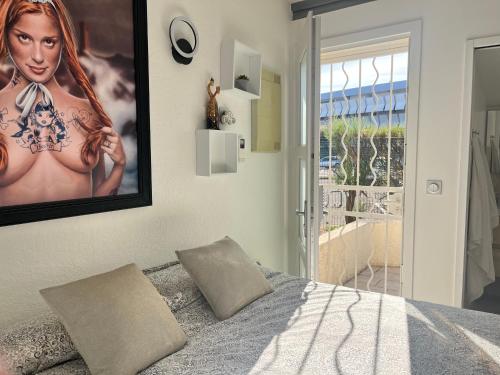 ein Schlafzimmer mit einem Poster einer Frau an der Wand in der Unterkunft BEGOOD'IZ naturiste Studio indépendant au calme au coeur du village in Cap d'Agde