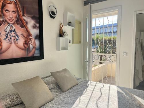 une chambre avec une affiche d'une femme sur le mur dans l'établissement BEGOOD'IZ naturiste Studio indépendant au calme au coeur du village, au Cap d'Agde