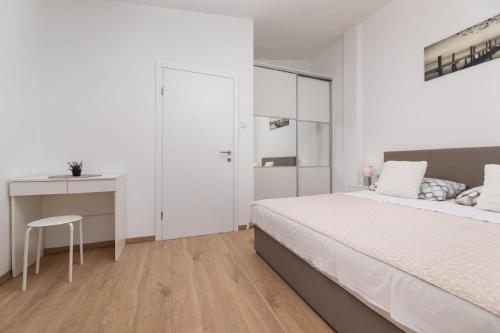 a white bedroom with a bed and a desk at Ferienwohnung für 4 Personen ca 50 qm in Njivice, Kvarner Bucht Krk in Njivice