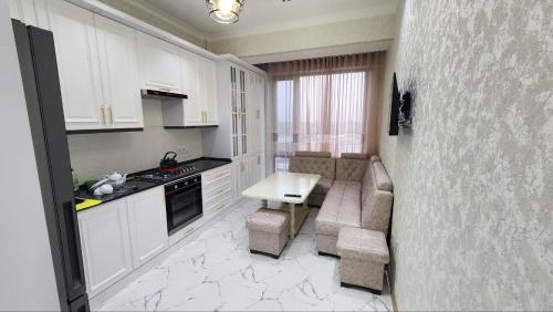 - une cuisine avec des placards blancs, une table et des chaises dans l'établissement Апартамент 2, à Samarcande