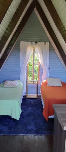 two beds in a attic room with a window at Cabañas Refugio verde in El Soberbio