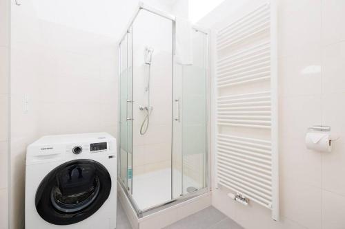 La salle de bains est pourvue d'un lave-linge et d'une douche en verre. dans l'établissement Modern Apartment near City Center - 2BR, Netflix, à Vienne