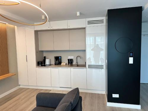 a kitchen with white cabinets and a couch in a room at Sunny Haven Wave SEA VIEW 8th Floor in Międzyzdroje