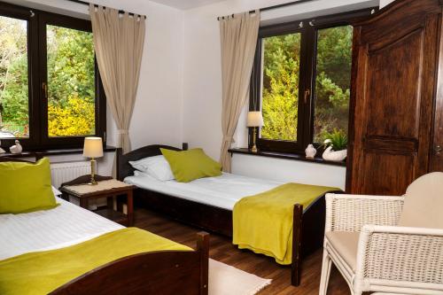 two beds in a room with two chairs and windows at Galikowo in Płaska