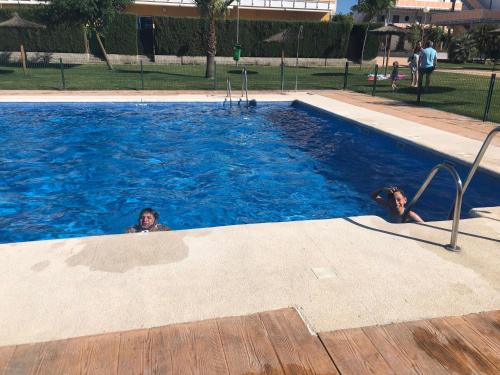 two people are swimming in a swimming pool at Apartamento en Costa Ballena in Cádiz