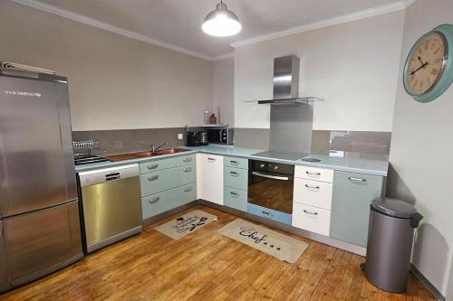 une cuisine équipée d'appareils en acier inoxydable et d'une horloge murale. dans l'établissement Cœur de Ville au pied du funiculaire, à Thonon-les-Bains