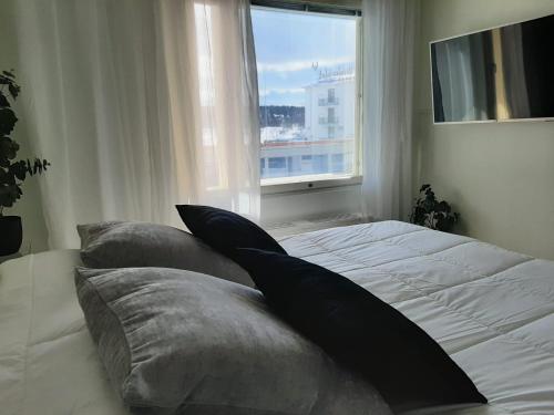 een bed met kussens in een slaapkamer met een raam bij RIVER VIEW & CENTRAL LOCATION - private sauna & glazed balcony in Rovaniemi