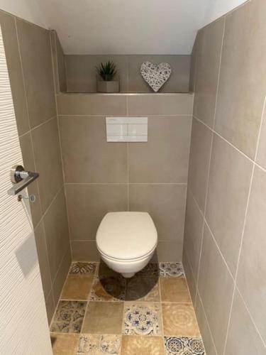 - une salle de bains avec des toilettes blanches dans une cabine dans l'établissement Maison de ville avec terrasse, à Lion-sur-Mer