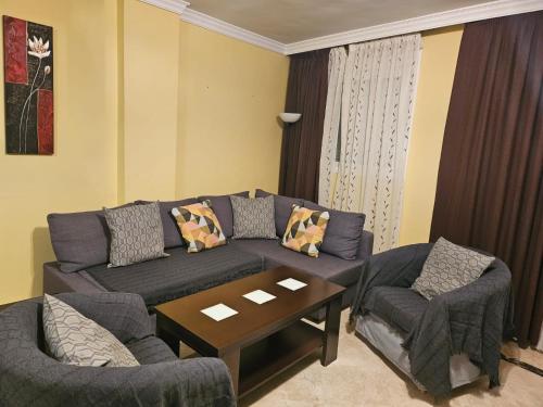 een woonkamer met een bank, 2 stoelen en een tafel bij 3 bedroom apartment with pool & parking, close to sea and golf in Manilva
