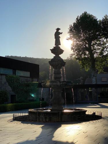 a statue of a woman sitting on top of a fountain at CASA do CAMPO Lestrove in Padrón