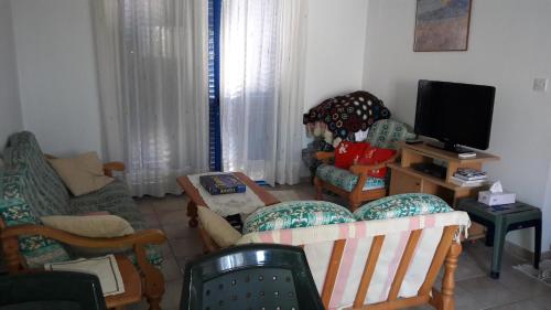 a living room with several chairs and a tv at Rita SeaView Apartment in Pervolia