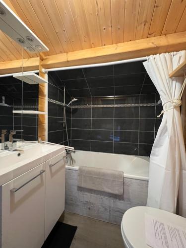 ein Badezimmer mit einer Badewanne, einem Waschbecken und einem WC in der Unterkunft Le Chalet « au Fil de l’eau » 