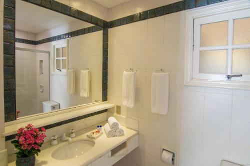 a white bathroom with a sink and a mirror at Hotel Doce Mar in Búzios
