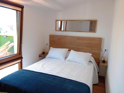 1 dormitorio con cama y espejo en la pared en A PINTEGA DAS DUNAS en Ribeira