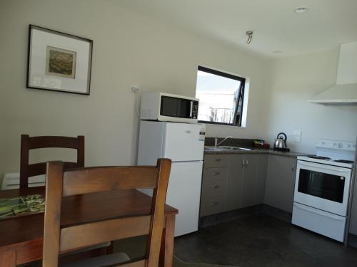 a small kitchen with a table and a white refrigerator at Oak Lodge in Greymouth