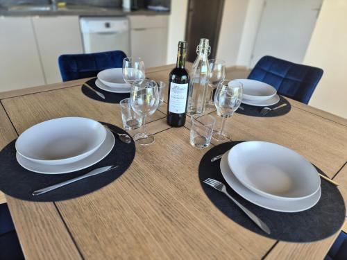 a table with plates and glasses and a bottle of wine at Maison paisible et agréable in Salles-Curan